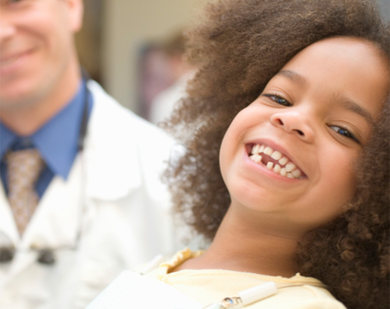 Niña sonriente en consulta con odontólogo