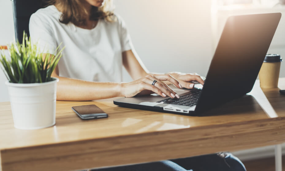 Mujer trabajando en laptop sobre escritorio de madera