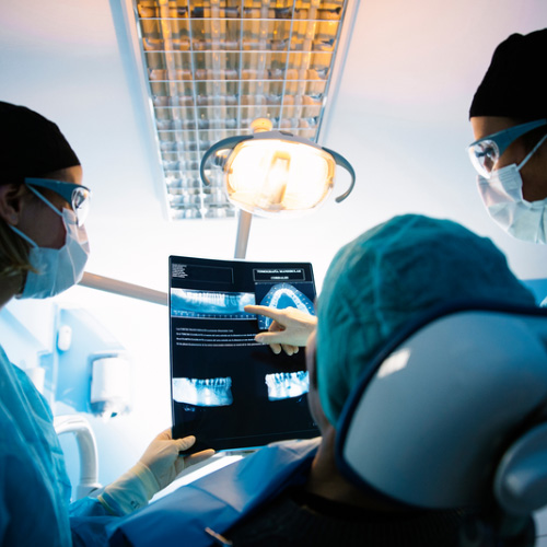Dentistas analizando radiografía dental con un paciente, diagnóstico en odontología