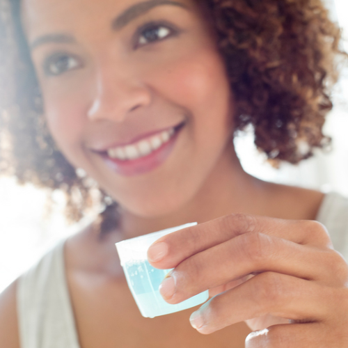 Mujer sosteniendo enjuague bucal