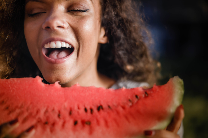 Mujer comiendo una sandia y mostrando una sonrisa blanca